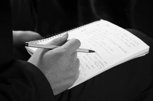 Eine Hand und ein großes Notizheft © Tom Rübenach