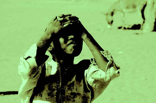 Ein Junge aus einem Flüchtlingslager verschränkt seine Arbe auf dem Kopf. Das Bild ist in grün gehalten. Foto © Tom Rübenach